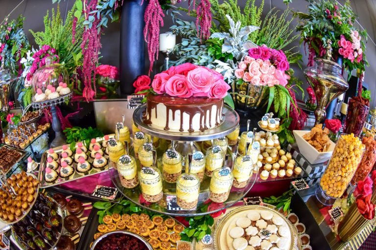 Mesa de postres de un evento con pastel de rosas, macarons y arreglos florales