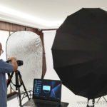 Fotógrafo montando iluminación de estudio con sombrilla y reflector para retrato corporativo